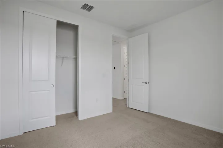Unfurnished bedroom featuring light carpet and a closet