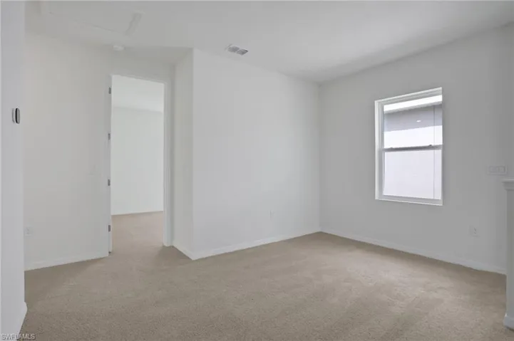 Empty room featuring light colored carpet and baseboards