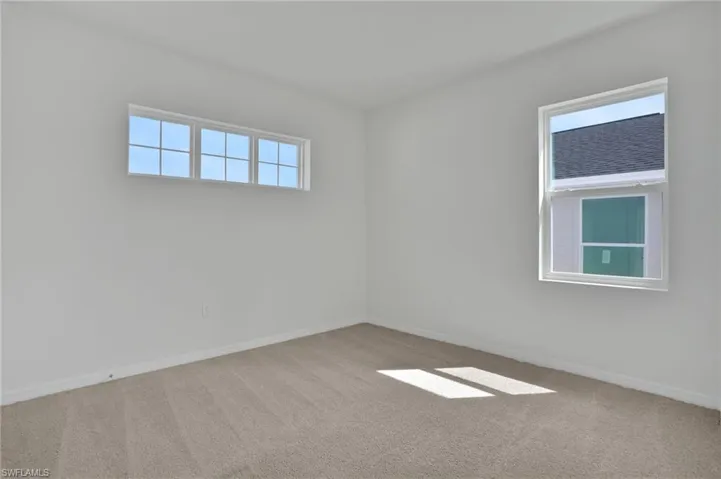 Carpeted spare room featuring baseboards