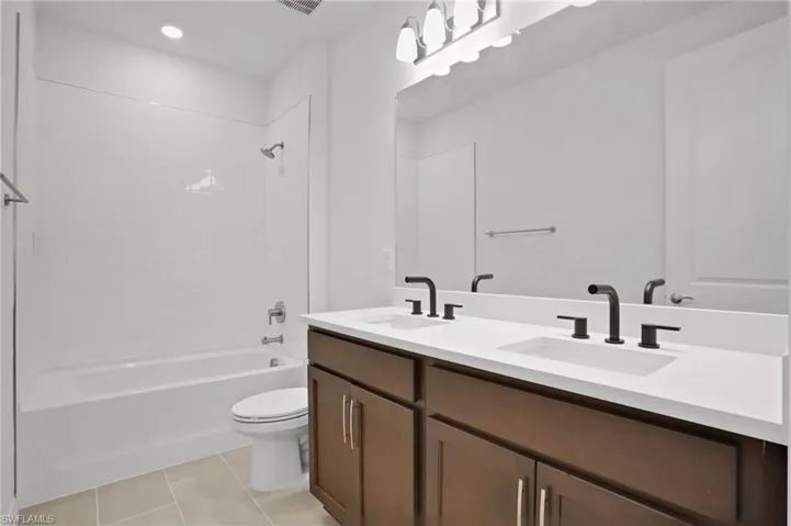 Full bath with double vanity,  shower combination, light tile patterned floors, and recessed lighting