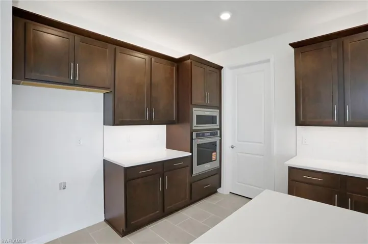 Kitchen with stainless steel appliances, dark wood finish cabinets, tasteful backsplash, and recessed lighting