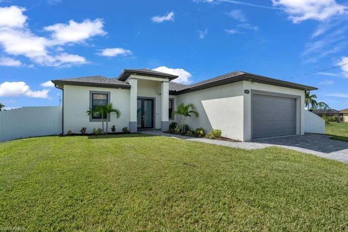 Ranch house featuring a garage, stucco siding, and paver driveway