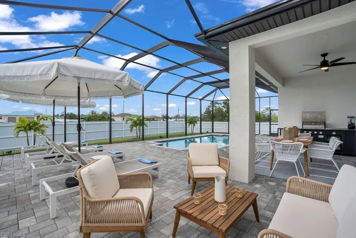 View of patio with a lanai, a ceiling fan, a sunroom, outdoor lounge area, and an outdoor kitchen