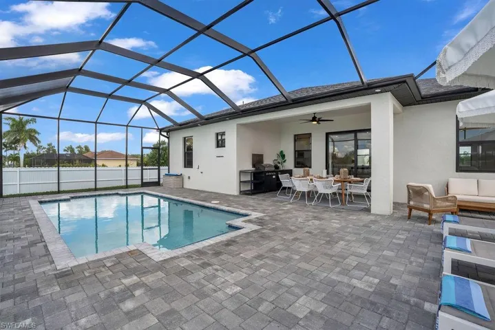 View of swimming pool featuring a lanai, a sunroom, a patio area, and outdoor dining area