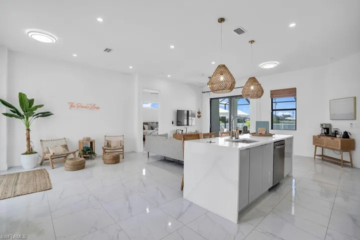 Kitchen featuring pendant lighting, light stone counters, a kitchen island with sink, modern cabinets, and open floor plan