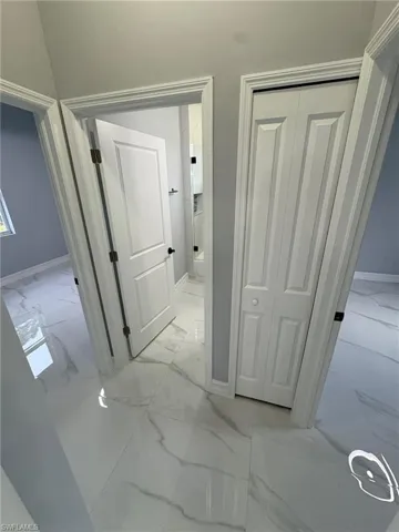 Hall featuring light marble finish floors and baseboards
