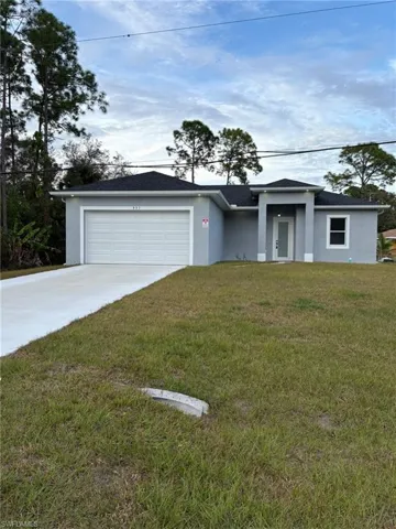 View of front of home featuring stucco siding, a front yard, driveway, and an attached garage