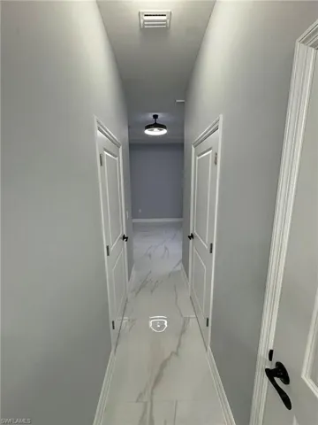 Hall featuring light marble finish floors and baseboards