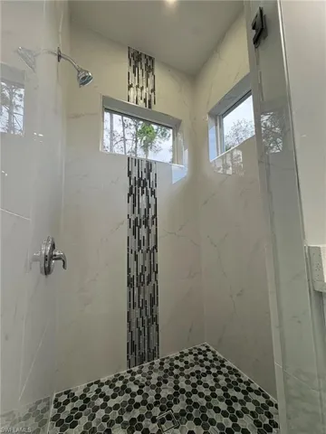 Full bath featuring a marble finish shower and healthy amount of natural light
