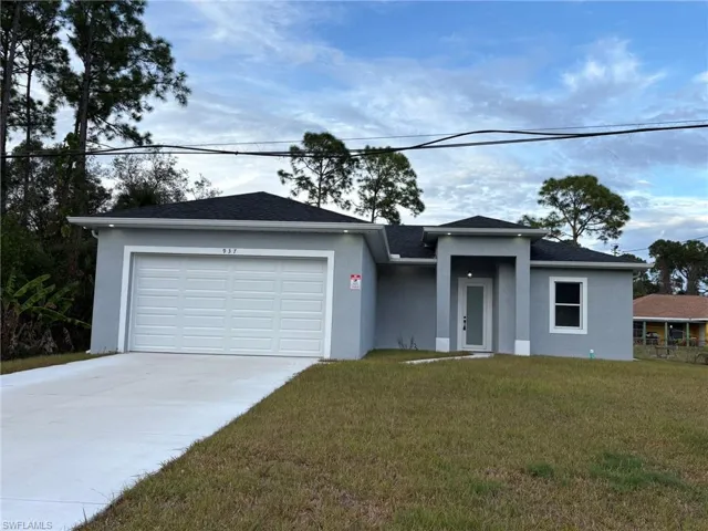 View of front facade with stucco siding, an attached garage, concrete driveway, and a front yard