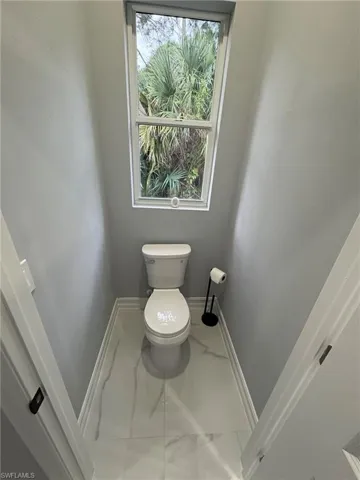 Bathroom with marble look tile flooring and toilet