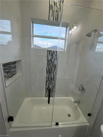 Bathroom featuring a combined bath / shower with marble appearance and plenty of natural light