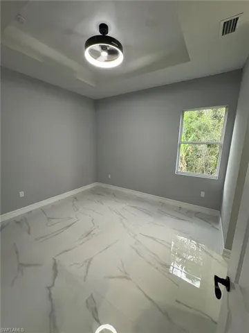 Empty room with a raised ceiling and marble look tiles