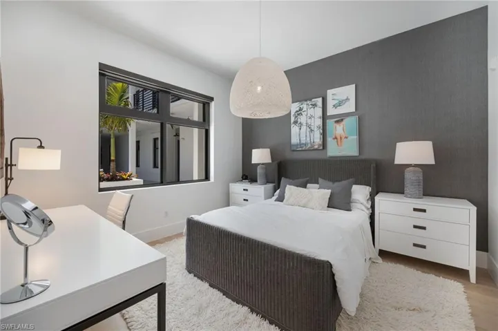 Bedroom featuring an accent wall, a desk, and light wood finished floors