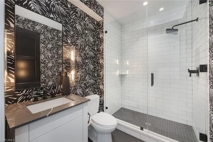 Bathroom with wallpapered walls, vanity, a shower stall, and recessed lighting