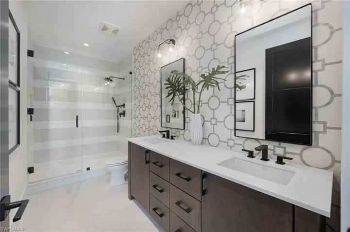 Bathroom with a stall shower, double vanity, and light tile patterned flooring