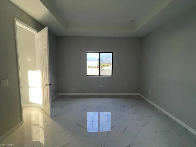 Tiled empty room featuring a raised ceiling