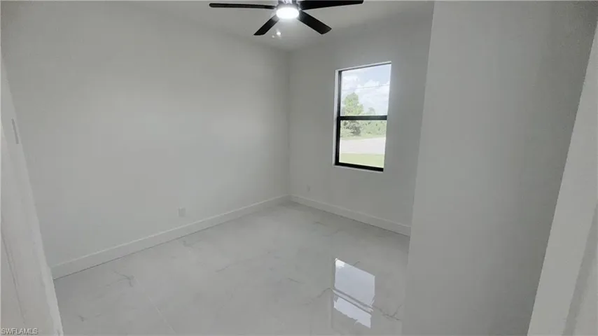 Empty room featuring light marble finish floors and a ceiling fan