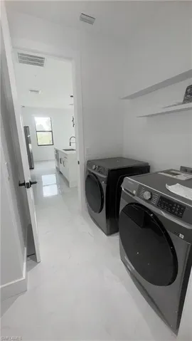 Washroom featuring light marble finish floors and independent washer and dryer