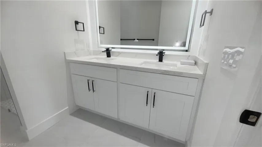 Bathroom featuring double vanity and light marble finish flooring