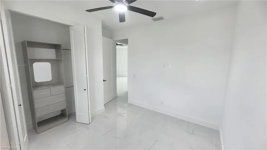 Unfurnished bedroom featuring light marble finish flooring, a closet, and a ceiling fan