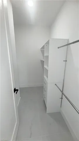 Walk in closet with light marble finish floors