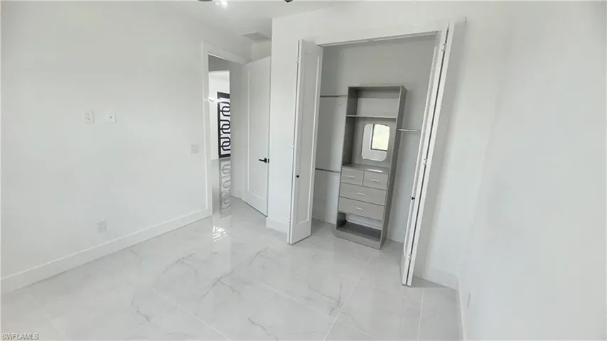 Unfurnished bedroom featuring light marble finish floors and a closet