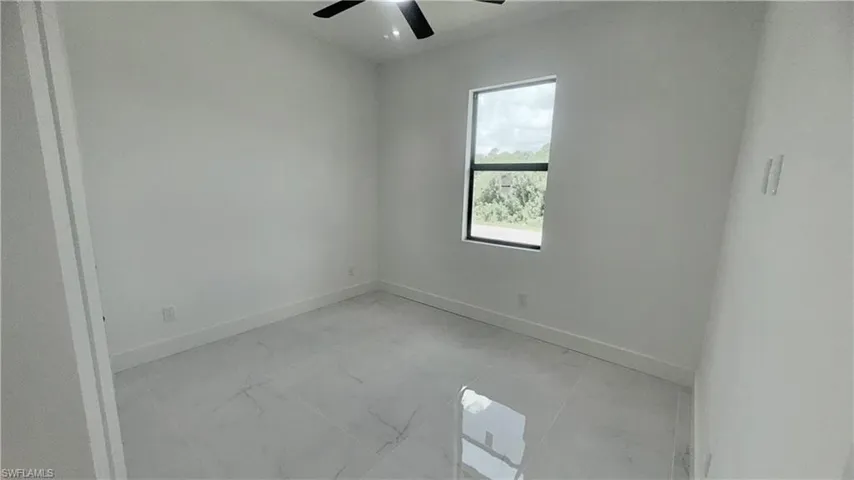 Empty room with light marble finish floors and a ceiling fan