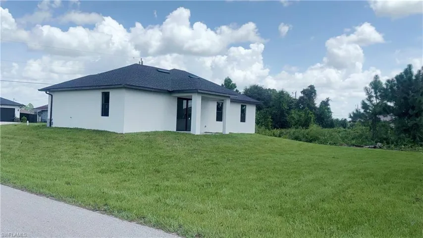 Back of house with a lawn, stucco siding, and roof with shingles