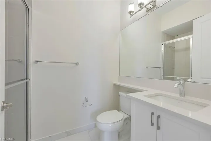 Bathroom featuring toilet, a shower with door, vanity, and tile patterned flooring
