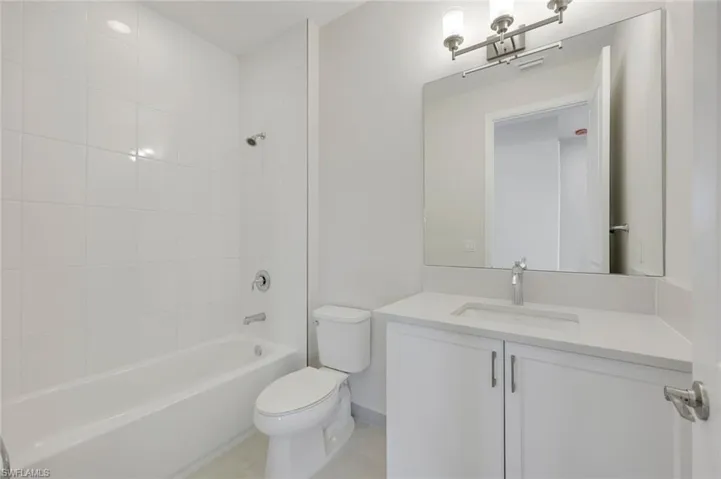 Full bathroom featuring vanity, toilet, tile patterned flooring, and tiled shower / bath combo