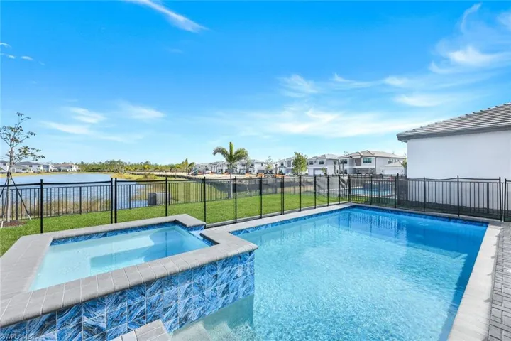 View of pool with a lawn, an in ground hot tub, and a water view