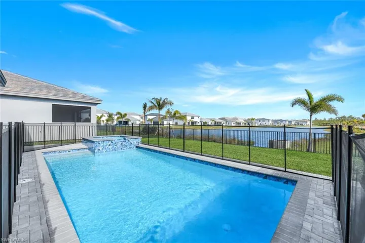 View of swimming pool featuring a lawn, an in ground hot tub, and a water view