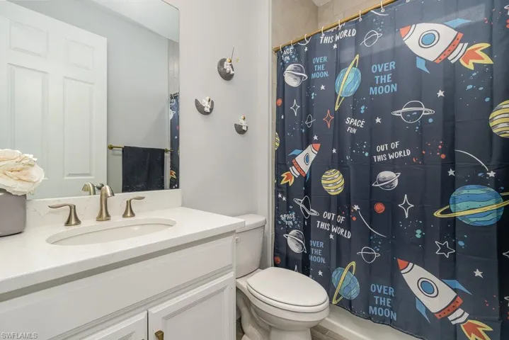 Bathroom with a shower with curtain, vanity, and toilet