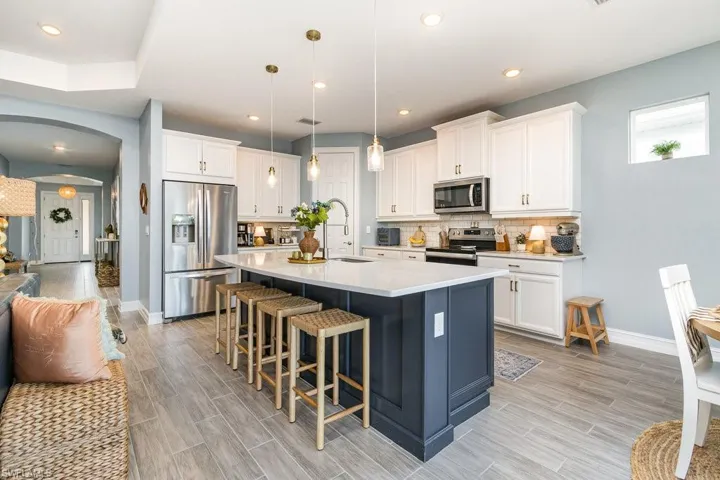 Kitchen with pendant lighting, white cabinetry, a kitchen island with sink, and appliances with stainless steel finishes