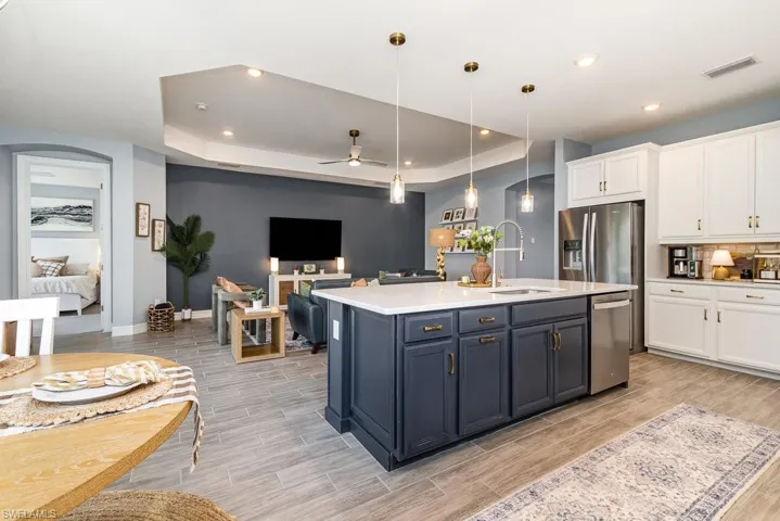 Kitchen featuring white cabinets, sink, ceiling fan, decorative light fixtures, and stainless steel appliances
