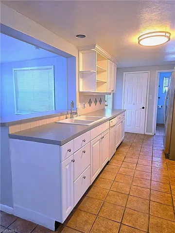 Kitchen featuring white cabinets, tasteful backsplash, light tile patterned floors, and a textured ceiling