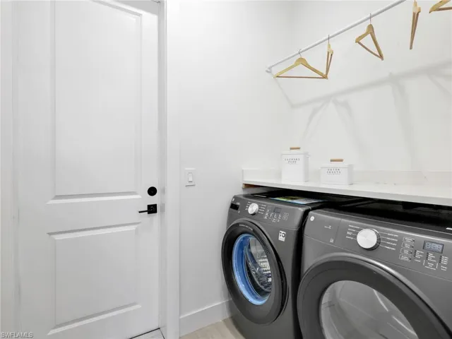 Dedicated laundry area featuring a white paneled door with black hardware, light-toned countertop, and an integrated hanging rod