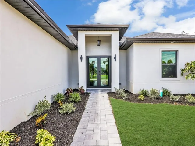 Modern stucco exterior with dark trim and a prominent covered entryway
