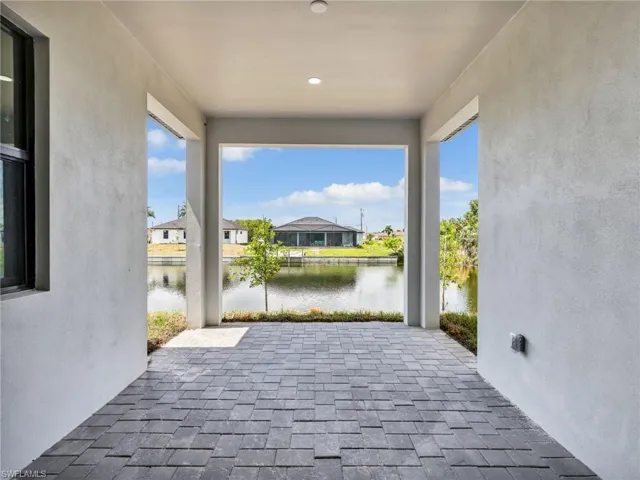 Covered patio featuring textured stone paver flooring and a water view
