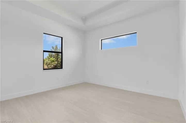 Bright interior space featuring light wood-finish flooring, white baseboards, and clean white walls