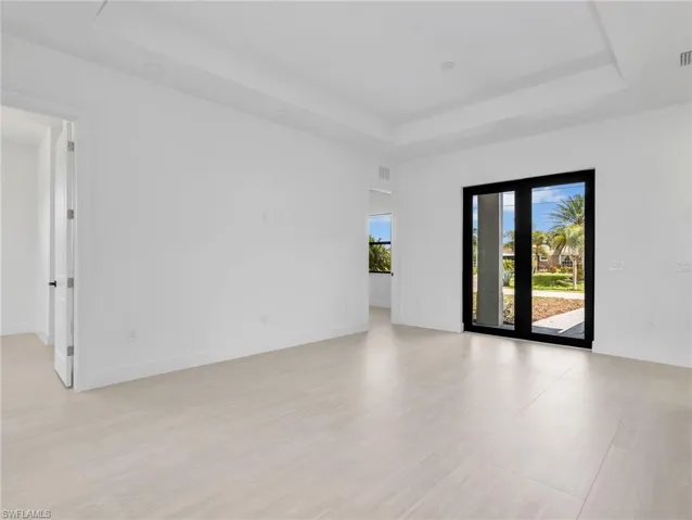 Spacious interior featuring light-toned tile flooring, white walls, and a tray ceiling with recessed lighting