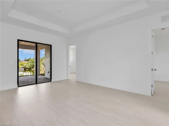 Expansive interior space featuring light-toned tile flooring and a tray ceiling