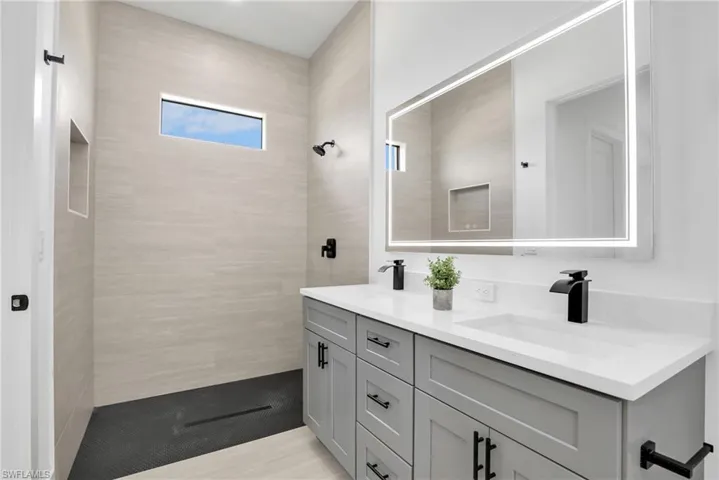 Modern bathroom featuring a dual vanity with light gray cabinetry, white countertops, and matte black fixtures