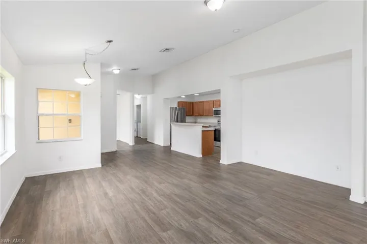 Unfurnished living room featuring dark wood finished floors and baseboards