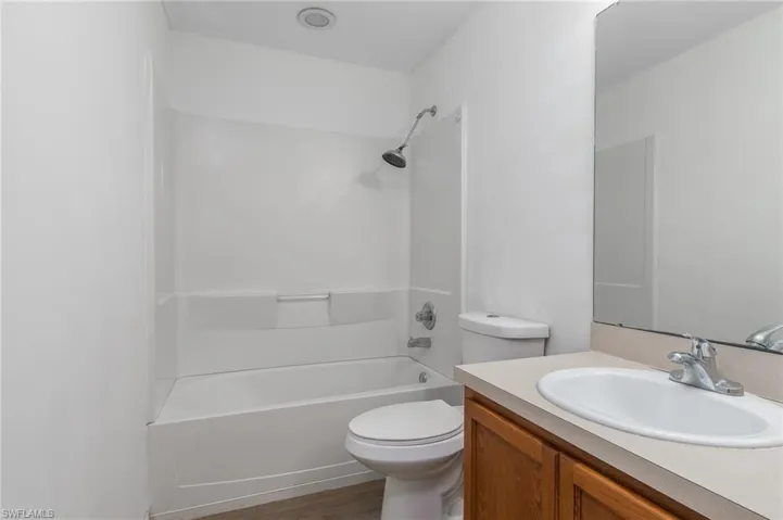 Bathroom featuring tub / shower combination, vanity, and dark wood finished floors