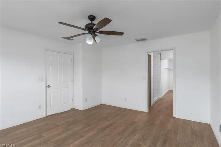 Empty room with dark wood finished floors and ceiling fan