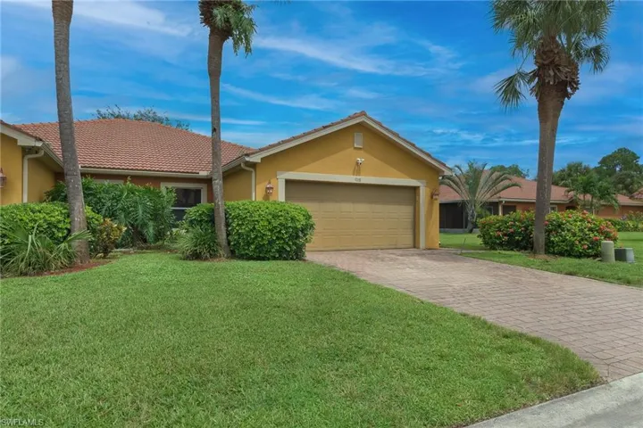 Ranch-style home with stucco siding, decorative driveway, an attached garage, a front yard, and a tiled roof