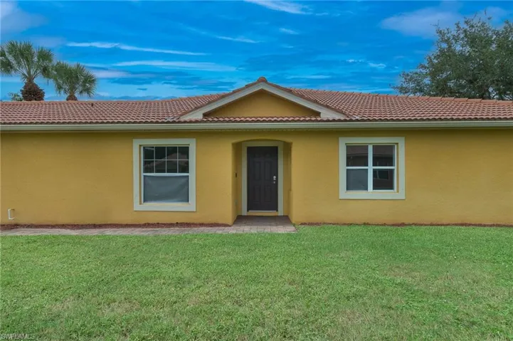 View of front of home featuring a front lawn, stucco siding, and a tiled roof