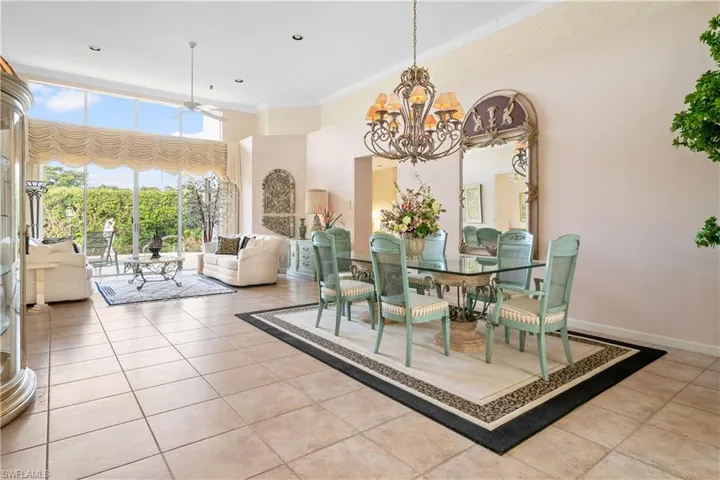 Tiled dining room with ceiling fan with notable chandelier and crown molding